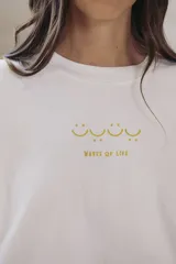 Remera blanca de algodón con estampa rectangular en tonos beige y texto negro.