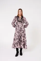 Vestido largo color rosa con estampado floral en negro, escote en V con ribete negro y mangas largas abullonadas.