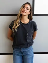 Remera gris de algodón con cuello redondo, mangas cortas y bolsillo en el pecho. Apliques de tachas plateadas en cuello, hombros y bolsillo.
