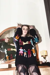 Sweater de lana negro con bordados de figuras humanas multicolores.