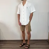 Bermuda color beige claro, estilo chino, confeccionada en gabardina. Presenta un corte recto y dobladillo en el ruedo.