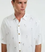 Camisa de viscosa con estampado de palmeras, corte relaxed, cuello inglés, manga corta y botones contrastantes.