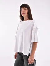Remera blanca de corte holgado con mangas cortas y detalle de rayas verticales negras en mangas y laterales.