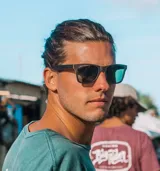 Lentes de sol con montura cuadrada de madera color negro y lentes verdes.