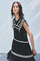 Minivestido negro de algodón con bordados florales blancos en cuello, mangas y ruedo.