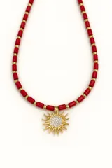 Collar corto de cuentas tubulares color rojo coral, separadas por pequeñas cuentas doradas. Dije de sol dorado con centro de circonias.
