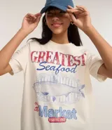 Remera t-shirt de algodón color crema, con cuello redondo y mangas cortas. Estampa frontal con la frase "Greatest Seafood" y un dibujo de un pez.