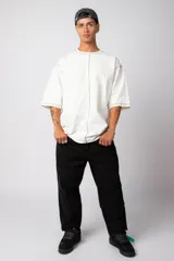 Remera negra oversize con mangas cortas y costuras a la vista en color blanco.