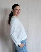 Remera blanca de mangas largas con cuello en V y costuras a la vista.