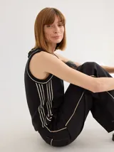 Chaleco tejido negro con detalles en contraste color crema, de corte relajado y sin mangas.