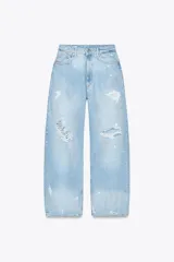 Pantalón de jean celeste claro, corte baggy, tiro medio, largo hasta el tobillo y con roturas grandes en ambas piernas.