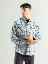 Camisa de franela a cuadros rojos, negros y grises, de manga larga y corte clásico, con dos bolsillos en el pecho.