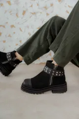 Bota corta de cuero gamuzado color marrón chocolate, con punta cuadrada y suela track. Presenta una correa con hebilla desmontable y cierre lateral con cremallera.