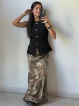 Chaleco negro de denim con corte peplum, cuello redondo y cierre frontal con botones dorados.