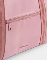 Bolso color beige de tela deportiva con manijas superiores y cierre superior. Tiene un bolsillo frontal con cierre y bolsillos laterales con cierre y tiradores de cordón y goma.