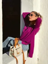 Cartera bandolera de cuero crudo con forro de tela, bolsillo frontal y bolsillo interno. Tiene correa larga regulable y manijas cortas de cuero marrón.