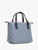 Cartera tote pequeña de lona a rayas verticales azules y blancas, con doble asa corta de mano y correa larga extraíble al hombro, ambas en cuero sintético azul marino. Tiene cierre superior con cremallera, bolsillo interno con cremallera y logo de Tommy Hilfiger en dorado en el frente.