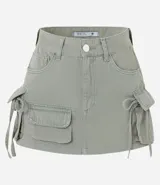 Minifalda color verde militar confeccionada en sarga de algodón. Cuenta con trabillas en la cintura, bolsillos cargo laterales con detalle de canalé colgando y cierre frontal tradicional.