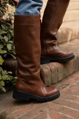 Bota alta color camel de cuero sintético, con suela track y cierre lateral.