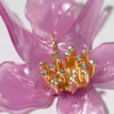 Par de aros colgantes con forma de flor color lila y centro dorado con strass.