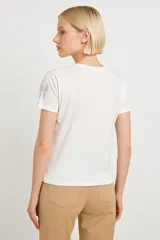 Remera blanca de algodón con cuello redondo y estampado de lazos plateados.