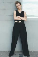 Pantalón negro de tiro medio con cinturón a tono con hebilla metálica, bolsillos delanteros y falsos bolsillos traseros.