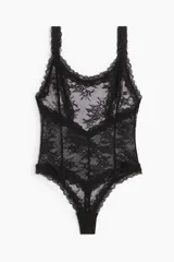 Body colaless de encaje negro transparente con breteles anchos y escote pronunciado en la espalda. Refuerzo interior con botones a presión ocultos.