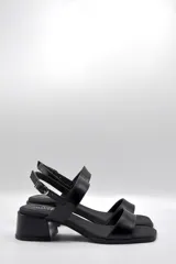 Sandalias de cuero negro con dos tiras anchas sobre el empeine, tira fina con hebilla al tobillo y taco cuadrado bajo.