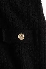 Minifalda negra de tweed con bolsillos frontales decorativos con botones dorados.