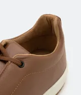 Championes marrones de cuero, con caña baja, ajuste con cordones y suela blanca.