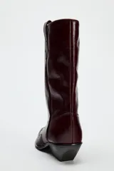 Bota de cuero color bordó, estilo cowboy, con puntera marcada y tiradores laterales.