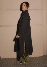 Trench negro confeccionado en algodón y nylon, repelente al agua, con largo midi, tajos laterales y bolsillos internos altos.