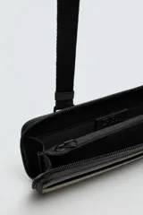 Bandolera tipo sobre color verde oliva con detalles en negro y acabado engomado. Tiene correa ajustable y extraíble, cierre de cremallera, seis ranuras para tarjetas, bolsillo interior con cremallera, dos bolsillos planos exteriores y mosquetón frontal.