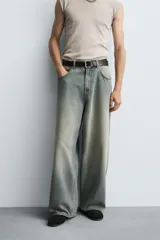 Pantalón de jeans de algodón, corte baggy fit, tiro medio, con efecto lavado en tonos grises y verdes. Presenta cinco bolsillos y cierre frontal con cremallera y botón.