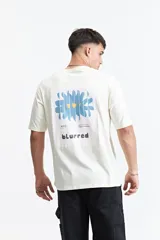 Remera oversize azul con estampado en la espalda de una flor abstracta en tonos rosa y amarillo sobre un fondo azul oscuro.