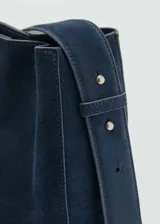 Bolso de mano marrón de piel serraje con asa corta ajustable y asa de hombro. Tiene forro interior, cierre de botón magnético y tamaño mediano.