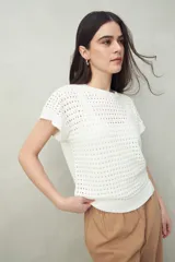 Chaleco tejido color crudo con diseño calado, cuello redondo y mangas cortas. Corte holgado.