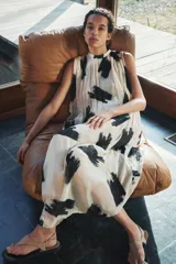 Vestido midi de Zara Woman Collection confeccionado en hilatura de viscosa color crudo con estampado abstracto en negro. Tiene cuello redondo, manga sisa, tejido plisado, forro interior y cierre en la espalda.