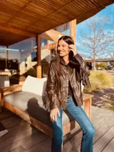 Campera de cuero color marrón claro, con flecos en la espalda y mangas.