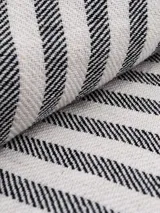Pareo rectangular de algodón color gris con rayas verticales blancas y flecos en los extremos.