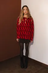 Cárdigan tejido con diseño de rombos rojos y negros, con mangas largas y cierre frontal con botones.