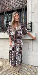 Vestido largo con estampado floral en tonos marrones, blancos y negros. Tiene escote en V, mangas cortas y corte holgado.