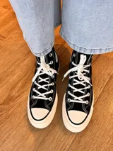 Zapatillas de lona blancas de caña alta con cordones y puntera de goma. Logo de durazno engomado en la base y en la cara interna.