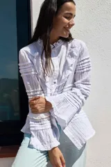Camisa blanca de algodón con cuello mao, volados en el frente y mangas largas con puños abotonados.
