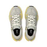 Championes de running On Cloudsurfer 2, color gris claro con detalles en amarillo y blanco.