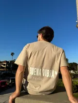Remera color beige de corte semi oversize con estampa blanca en la espalda con la frase "Buena Vibra" y "feel the vibes".