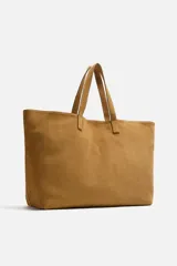 Bolso tipo shopper color marrón claro, fabricado en piel con acabado serraje. Tiene un compartimento principal con cierre imantado y un bolsillo interior con cremallera. Cuenta con dos asas de mano fabricadas en piel.