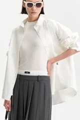 Camisa blanca de algodón con corte amplio y abotonadura frontal. Presenta un pequeño detalle bordado en un costado del frente.