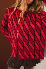 Cárdigan tejido con diseño de rombos rojos y negros, con mangas largas y cierre frontal con botones.