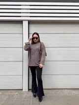 Sweater de punto con estampado animal print en tonos grises y marrones, cuello alto, corte holgado, más largo en la parte trasera y tajos laterales.